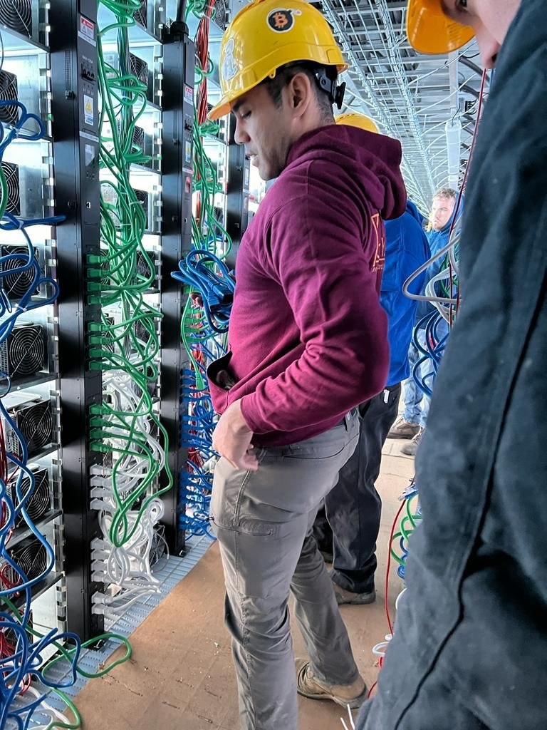 George in a hard hat installing bitcoin mining rigs